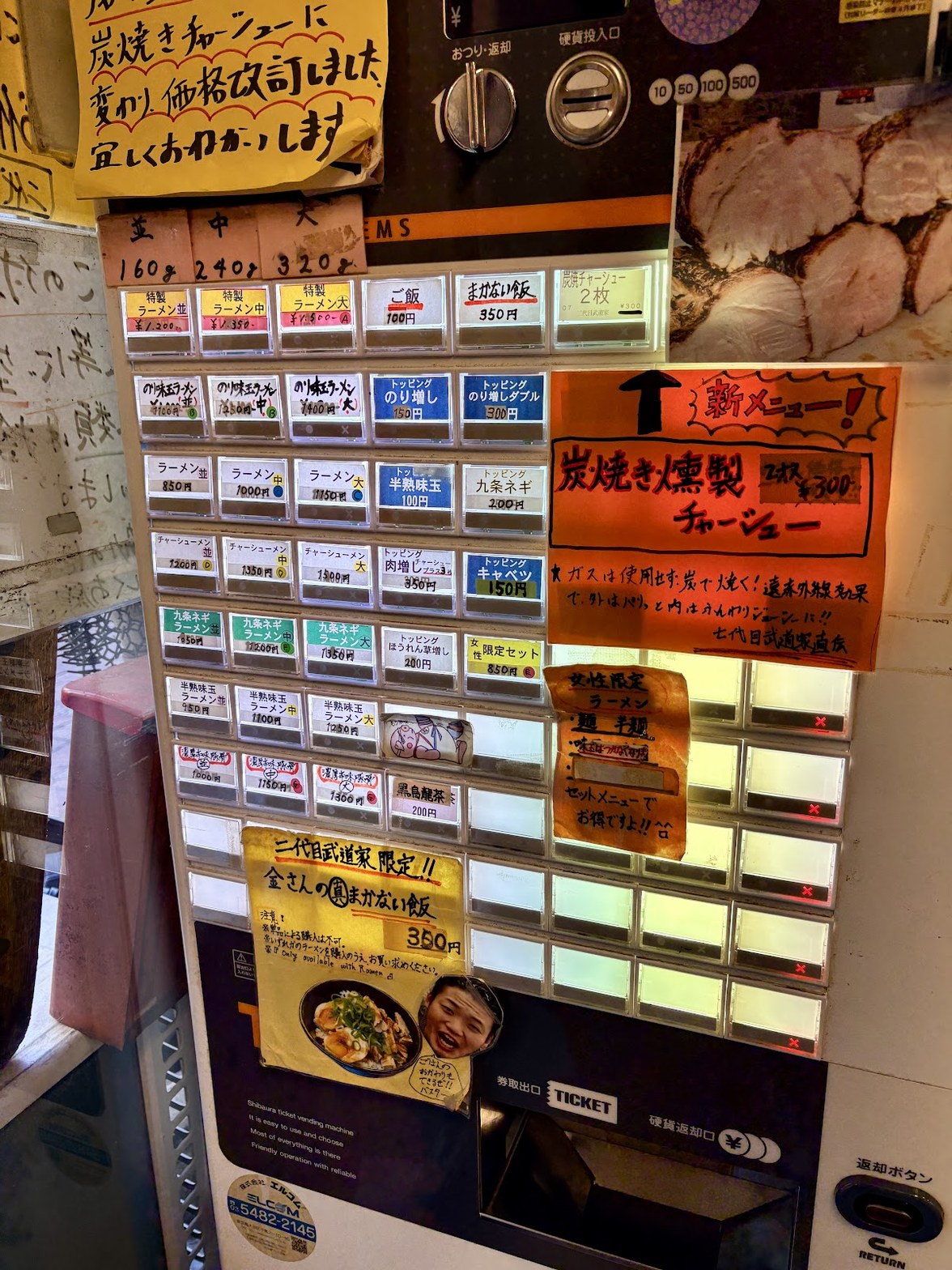 壁面に貼られた券売機、ラーメン並850円・中1000円など価格表示と炭焼き燻製チャーシューの新メニュー告知が並ぶ